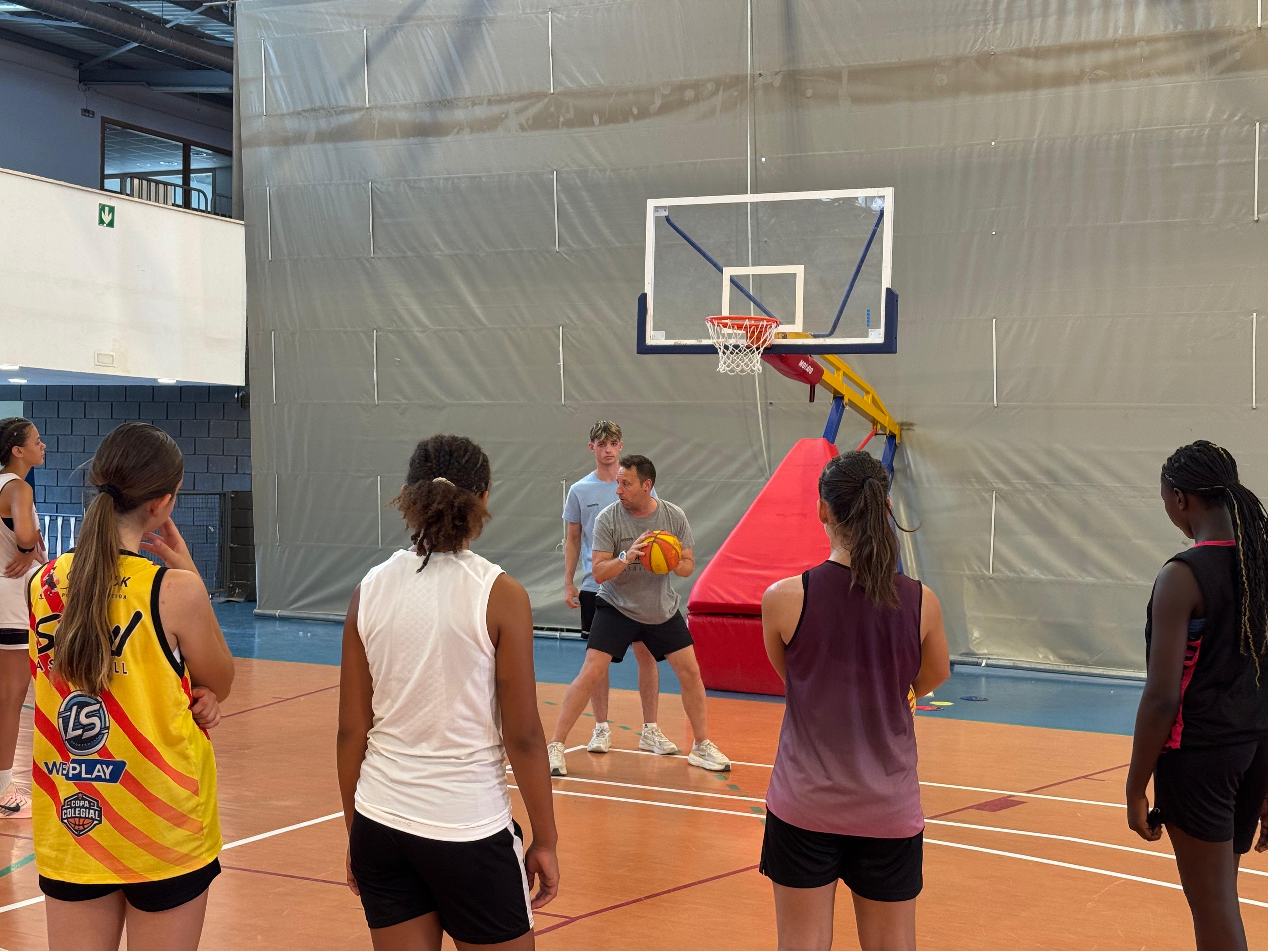 Un dels entrenadors ensenyant un moviment a les jugadores.